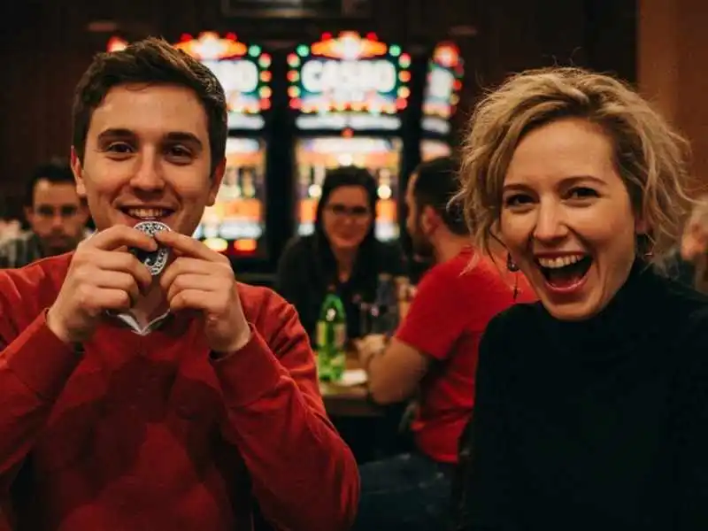 Smiling couple at a casino table holding chips, enjoying a Casino craps game